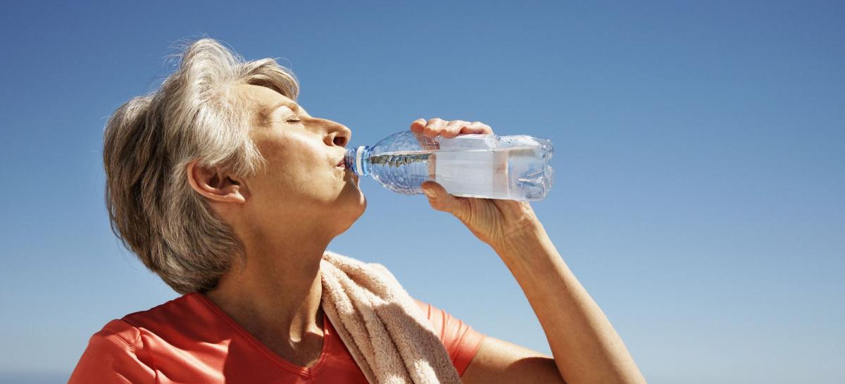 Foto di una persona anziana che beve da una bottiglietta d'acuqa